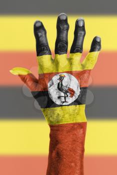 Hand of an old woman wrapped in flag of Uganda