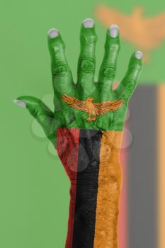Hand of an old woman wrapped in flag of Zambia