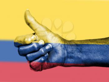 Old woman with arthritis giving the thumbs up sign, wrapped in flag pattern, Colombia