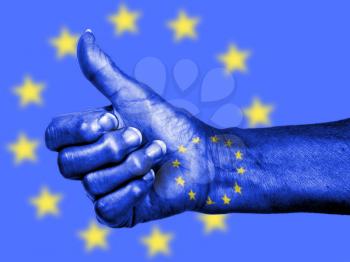 Old woman with arthritis giving the thumbs up sign, wrapped in flag pattern, European Union