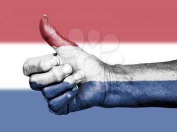 Old woman with arthritis giving the thumbs up sign, wrapped in flag pattern, Holland