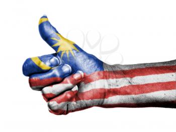 Old woman with arthritis giving the thumbs up sign, wrapped in flag pattern, Malaysia