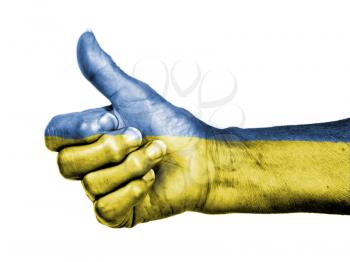 Old woman with arthritis giving the thumbs up sign, wrapped in flag pattern, Ukraine