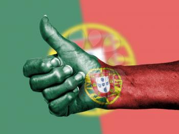 Old woman with arthritis giving the thumbs up sign, wrapped in flag pattern, Portugal