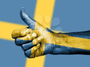Old woman with arthritis giving the thumbs up sign, wrapped in flag pattern, Sweden
