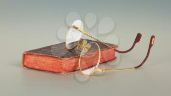 Very old glasses and a red book isolated on white background