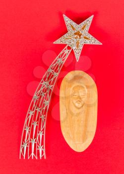 Falling star, christmas decoration and a carving of the baby Jezus, isolated on red
