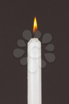 Burning white candle, isolated on black background