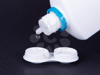 Lens casing and bottle of water isolated on black, contact lenses