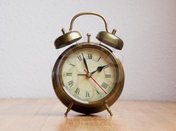 Retro alarm clock on a wooden table with a white wall