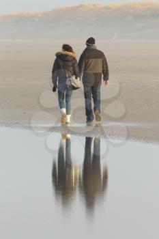 Couple walking on a dutch beach in the winter