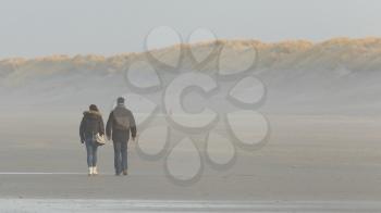 Couple walking on a dutch beach in the winter