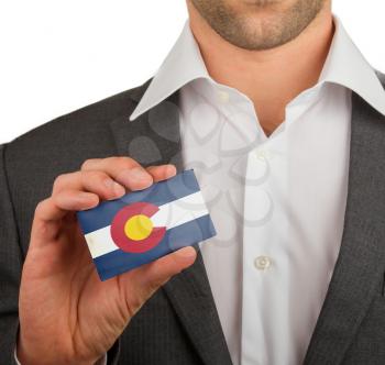 Businessman is holding a business card, flag of Colorado