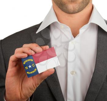 Businessman is holding a business card, flag of North Carolina