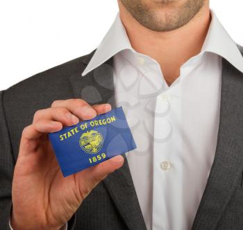 Businessman is holding a business card, flag of Oregon