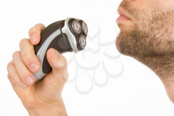Young man shaving his beard off with an electric shaver