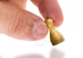 Hand holding wooden pawn with a painting, selective focus, gold