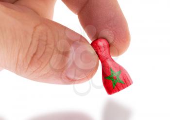 Hand holding wooden pawn with a flag painting, selective focus, Morocco