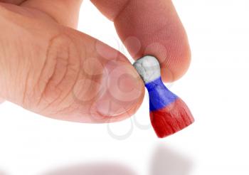Hand holding wooden pawn with a flag painting, selective focus, Russia