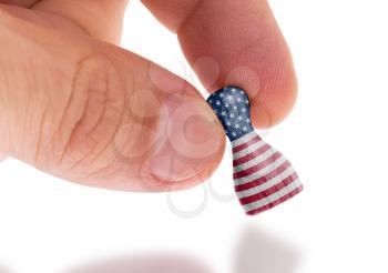 Hand holding wooden pawn with a flag painting, selective focus, United States of America