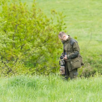 Wildlife photographer with long telephoto lens in action dress of camouflage