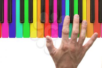 Rainbow piano keyboard with hand on white background