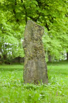 Wheatered old gravestone in a field of grass