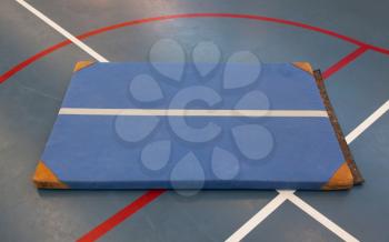 Very old blue mat on a blue court, school gym