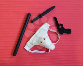 Groin protection and training weapons on a red mat