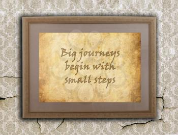 Old wooden frame with written text on an old wall - Big journeys, small steps