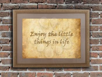 Old wooden frame with written text on an old wall - Enjoy the little things in life