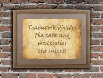 Old wooden frame with written text on an old wall - Teamwork divides the task and multiplies the success