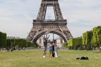 PARIS - JULY 27: Newly wed couple at the Eiffel Tower on July 27, 2013, in Paris. The Eiffel Tower is the most visited tourist attraction in France and one of the most recognizable landmarks in the wo