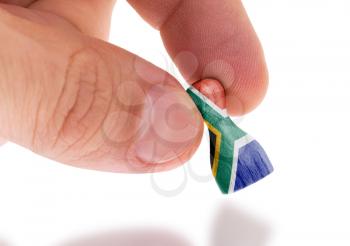 Hand holding wooden pawn with a flag painting, selective focus, South Africa