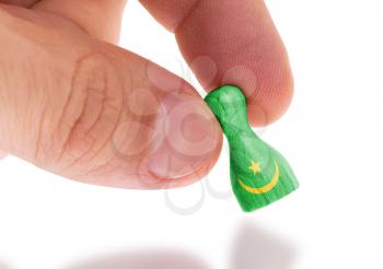 Hand holding wooden pawn with a flag painting, selective focus, Mauritania