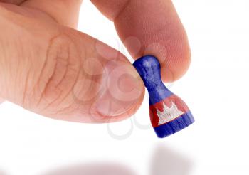 Hand holding wooden pawn with a flag painting, selective focus, Cambodia