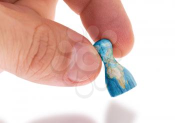 Hand holding wooden pawn with a map painting, selective focus, world map