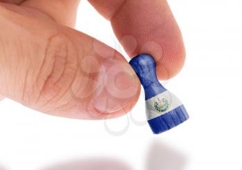Hand holding wooden pawn with a flag painting, selective focus, El Salvador