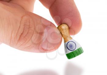 Hand holding wooden pawn with a flag painting, selective focus, India