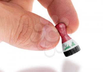 Hand holding wooden pawn with a flag painting, selective focus, Iraq