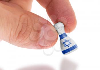 Hand holding wooden pawn with a flag painting, selective focus, Israel