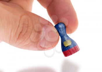 Hand holding wooden pawn with a flag painting, selective focus, Liechtenstein