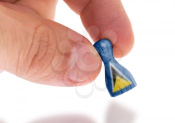 Hand holding wooden pawn with a flag painting, selective focus, Saint Lucia