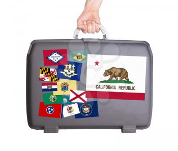 Used plastic suitcase with stains and scratches, stickers of US States, California
