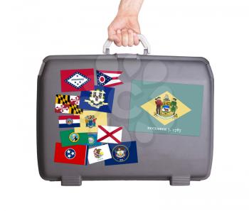 Used plastic suitcase with stains and scratches, stickers of US States, Delaware