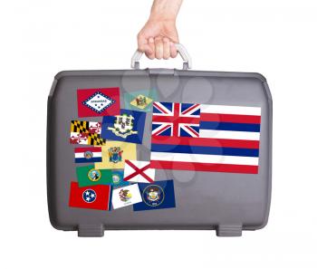 Used plastic suitcase with stains and scratches, stickers of US States, Hawaii