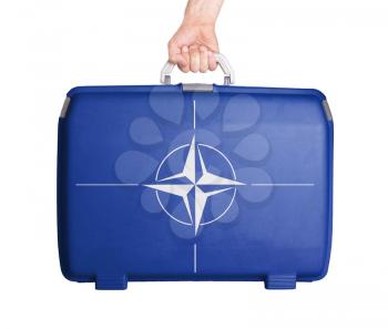 Used plastic suitcase with stains and scratches, printed with flag, NATO
