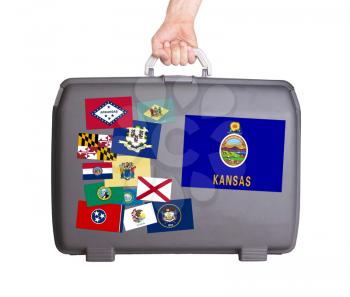 Used plastic suitcase with stains and scratches, stickers of US States, Kansas