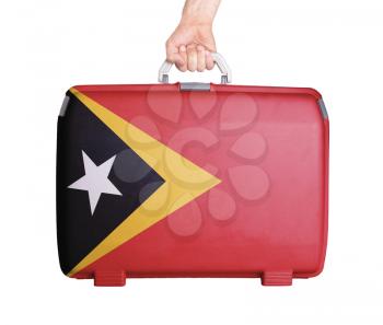 Used plastic suitcase with stains and scratches, printed with flag, East Timor