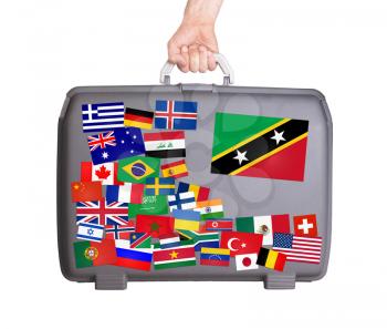 Used plastic suitcase with lots of small stickers, large sticker of Saint Kitts and Nevis